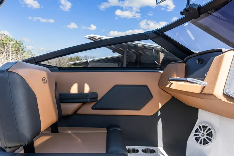 Slide: The Image of 2024 Cobalt CS23 Surf boat interior with tan and black seating, cup holders, and speaker. - 19
