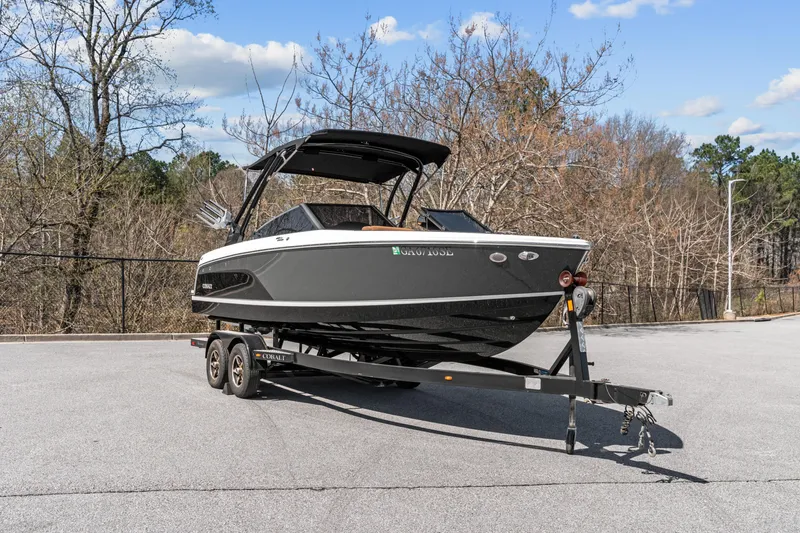 Slide: The Image of 2024 Cobalt CS23 Surf boat on trailer, parked outdoors, clear sky background. - 26
