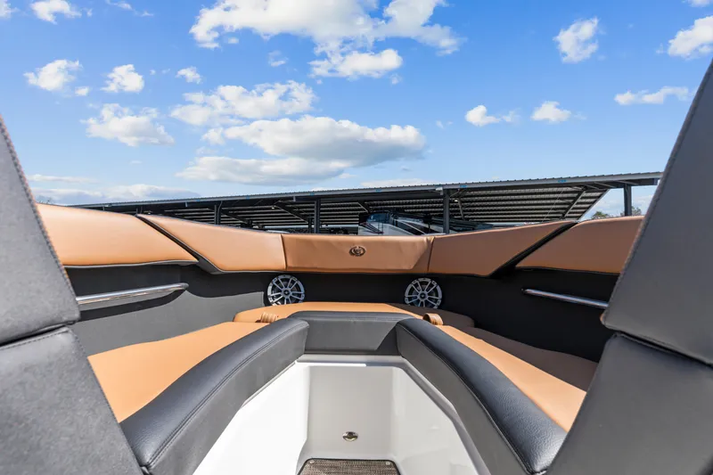Slide: The Image of 2024 Cobalt CS23 Surf boat interior with tan and black seating under blue sky. - 4