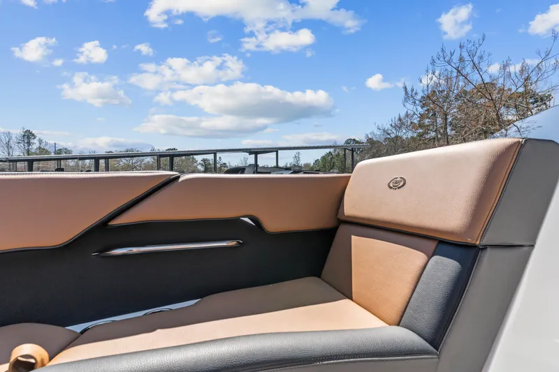 Slide: The Image of 2024 Cobalt CS23 Surf boat interior with tan and black seating under blue sky. - 5