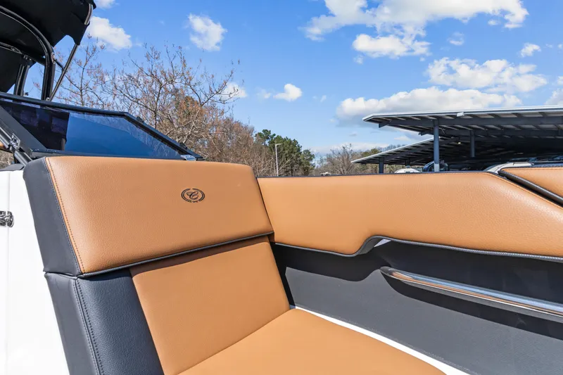 Slide: The Image of 2024 Cobalt CS23 Surf boat interior with tan and black seating under blue sky. - 6