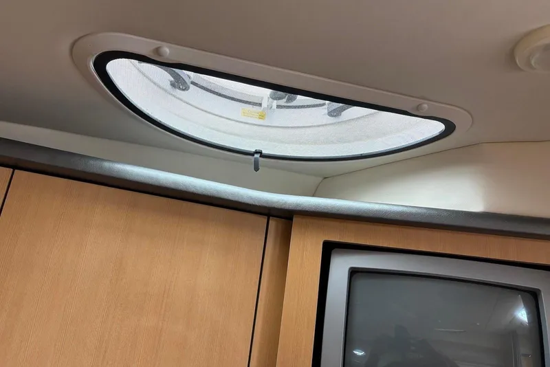 Slide: The Image of 2004 Maxum 3100 SE cabin interior with oval window and wooden cabinetry. - 15