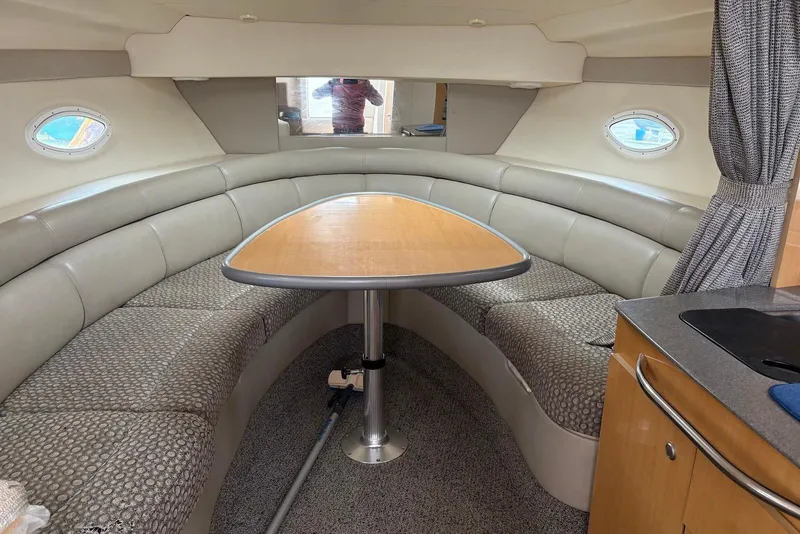 Slide: The Image of 2004 Maxum 3100 SE boat interior with curved seating and wooden table. - 8