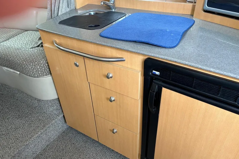 Slide: The Image of 2004 Maxum 3100 SE boat interior with kitchenette, featuring sink, countertop, and storage drawers. - 9