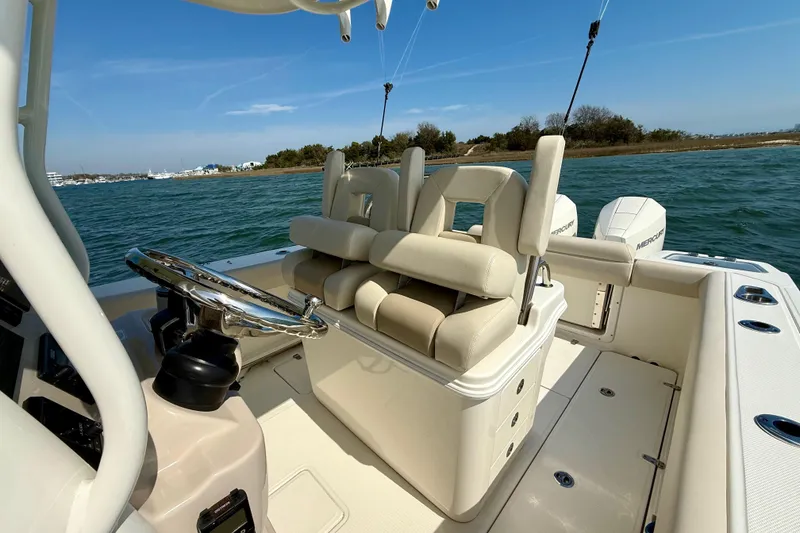 Slide: The Image of 2024 Boston Whaler 250 Outrage boat interior with helm and seating, on calm water. - 23