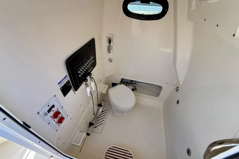 Slide: The Image of 2024 Boston Whaler 250 Outrage interior cabin with toilet and control panel. - 37