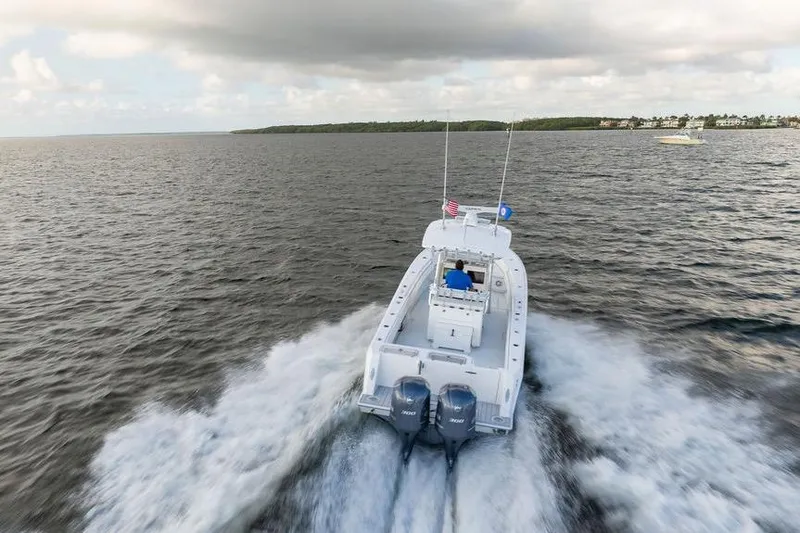 Slide: The Image of 2013 Contender 32 ST boat cruising on open water, rear view, with dual engines. - 10