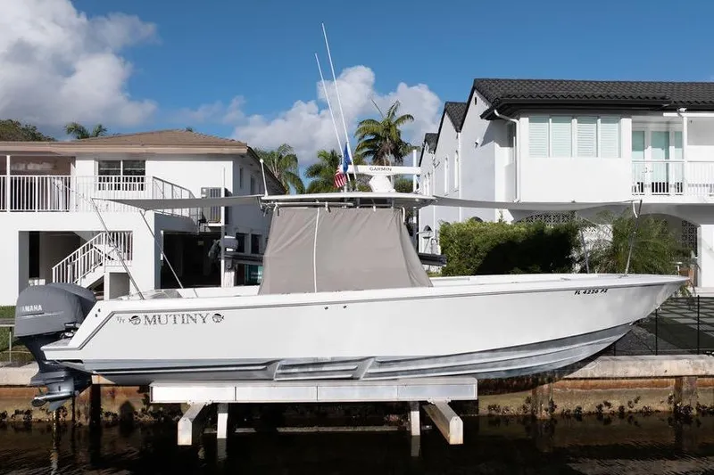 Slide: The Image of 2013 Contender 32 ST boat docked near waterfront homes, featuring Yamaha engines. - 22