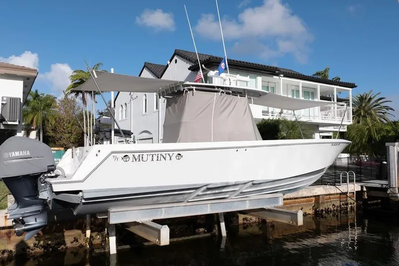 Slide: The Image of 2013 Contender 32 ST boat named "Mutiny" docked near waterfront home. - 23