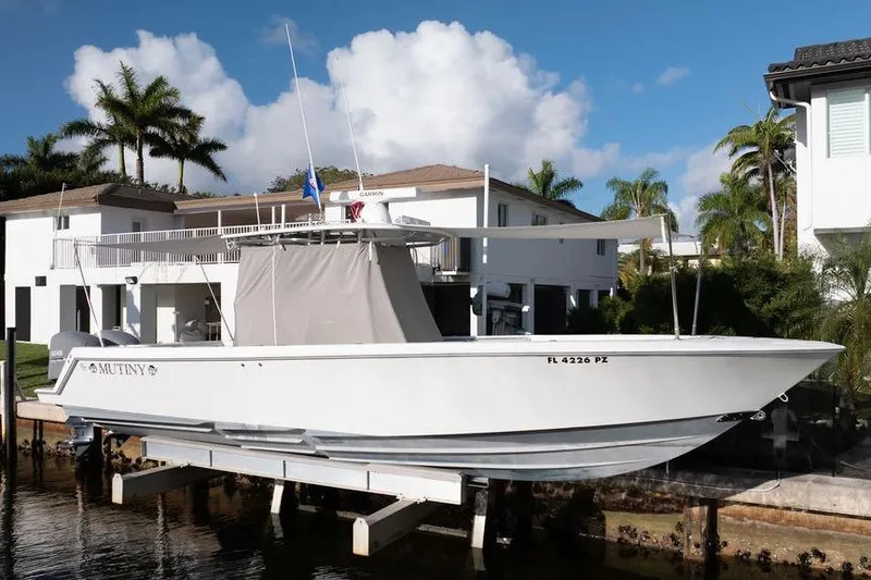 Slide: The Image of 2013 Contender 32 ST boat docked near waterfront homes, under a clear blue sky. - 24