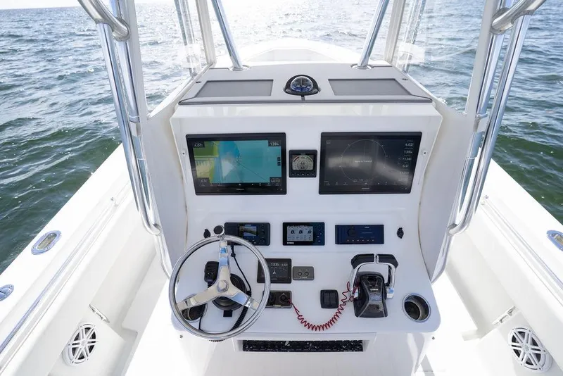 Slide: The Image of 2013 Contender 32 ST boat console with navigation screens and steering wheel on open water. - 26