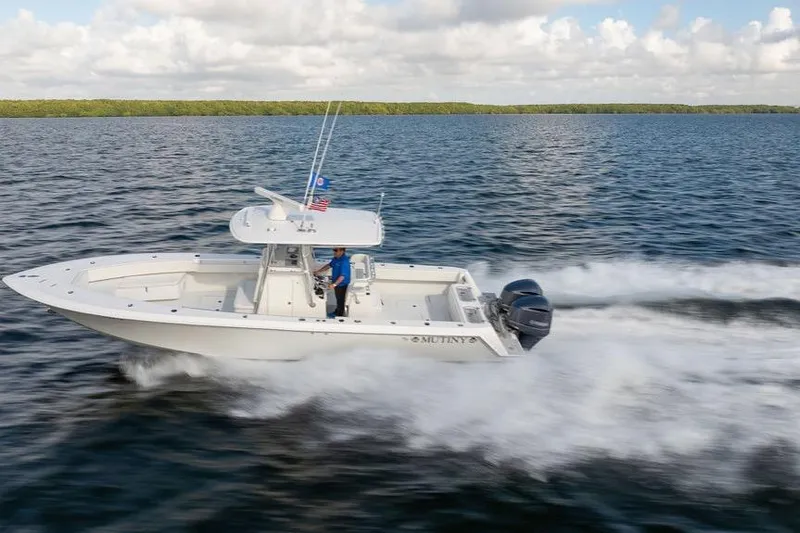 Slide: The Image of 2013 Contender 32 ST boat cruising on open water, clear sky, and lush shoreline. - 6