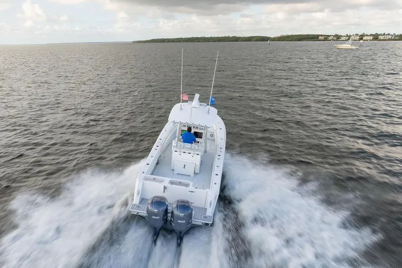 Slide: The Image of 2013 Contender 32 ST boat cruising on open water, rear view with twin engines. - 9