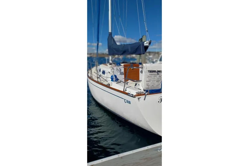 Slide: The Image of 1988 Tartan 28 sailboat docked, featuring a sleek white hull and blue sail cover. - 42