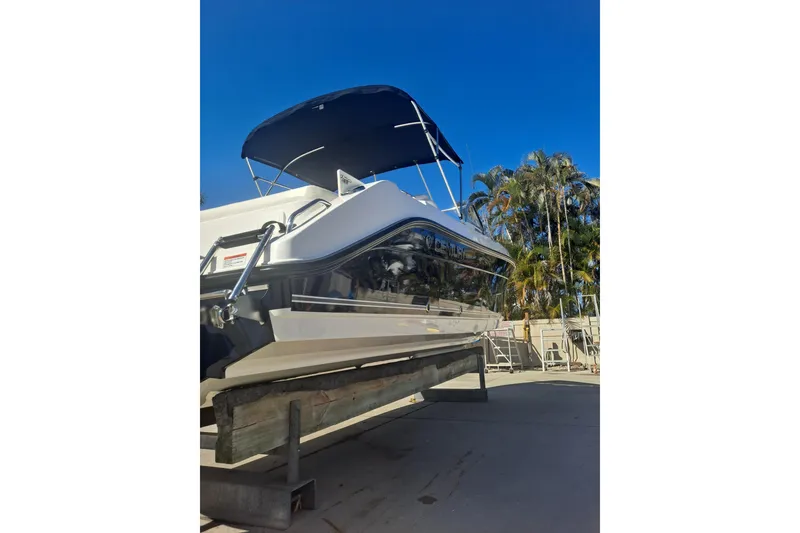 Slide: The Image of 2008 Century 2350 Dual Console boat on trailer, blue canopy, palm trees in background. - 6