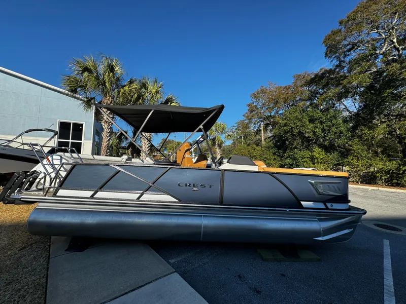 Slide: The Image of 2024 Crest Caribbean LX 230 pontoon boat displayed indoors with sleek design and canopy. - 2