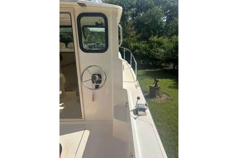 Slide: The Image of 2001 Parker 2320 Sport Cabin boat exterior with steering wheel and cabin door. - 13