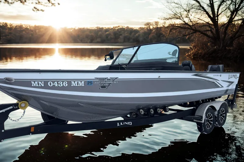 Slide: The Image of 2023 Lund 2175 Pro-V boat on trailer by serene lake at sunset. - 3