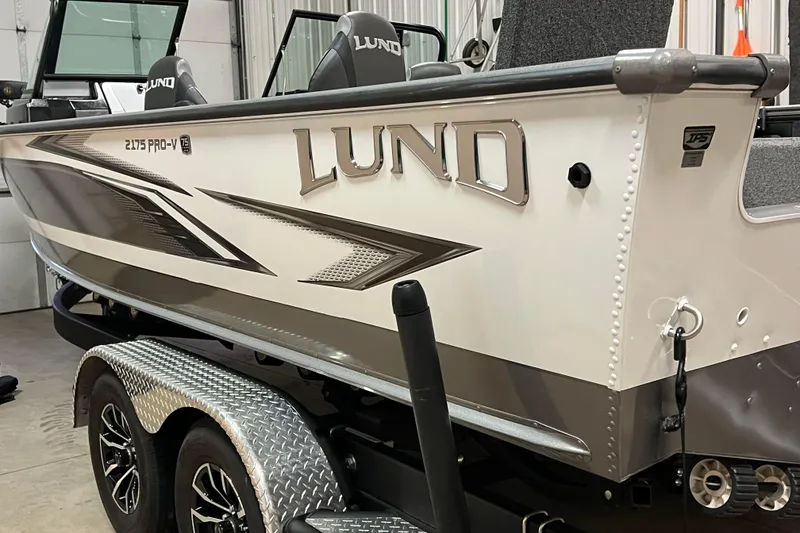Slide: The Image of 2023 Lund 2175 Pro-V boat on trailer in a garage setting. - 44