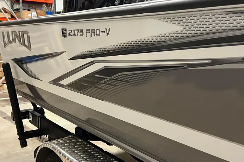 Slide: The Image of 2023 Lund 2175 Pro-V boat with sleek gray and white design on a trailer. - 56