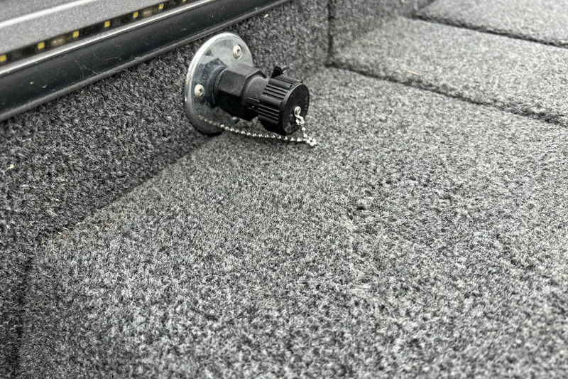 Slide: The Image of 2023 Lund 2175 Pro-V boat interior with carpeted flooring and a mounted socket. - 69