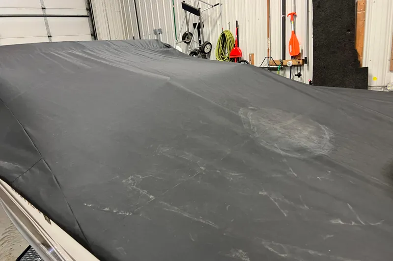 Slide: The Image of 2023 Lund 2175 Pro-V boat covered in a protective tarp inside a garage. - 76