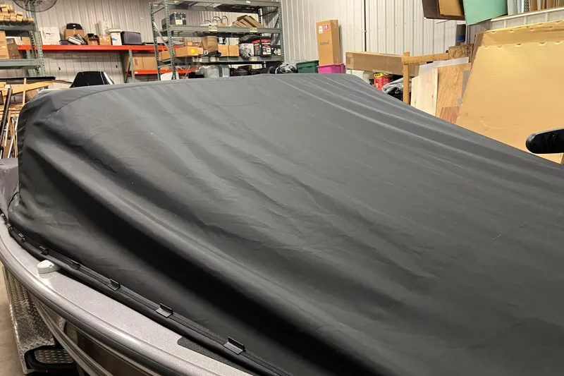 Slide: The Image of 2023 Lund 2175 Pro-V boat covered in a black tarp in a storage area. - 77