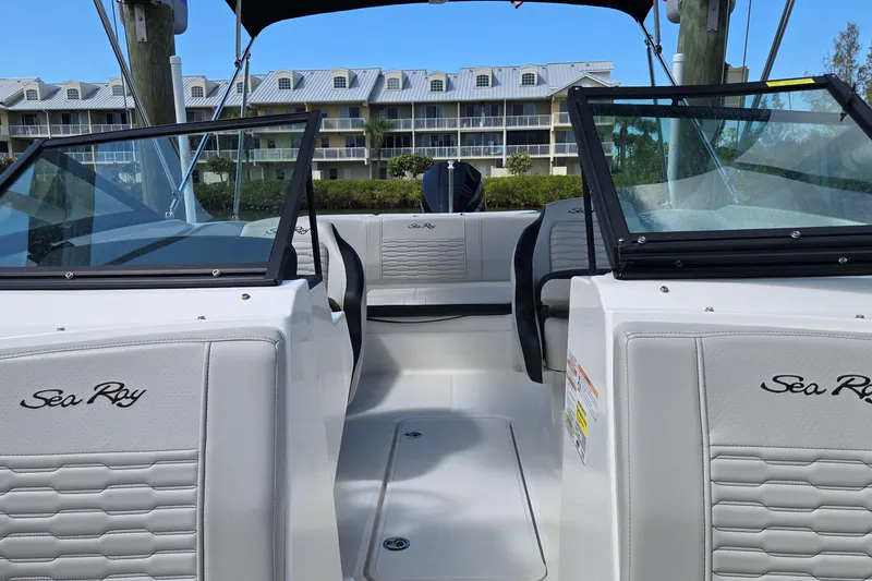 Slide: The Image of 2023 Sea Ray SPX 210 boat interior with modern seating and windshield, docked near buildings. - 16