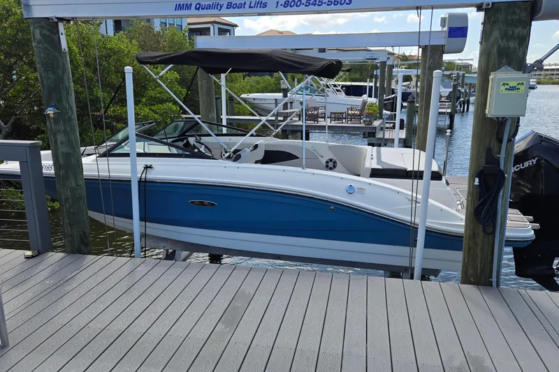 Slide: The Image of 2023 Sea Ray SPX 210 boat docked on a lift, featuring a sleek blue and white design. - 22