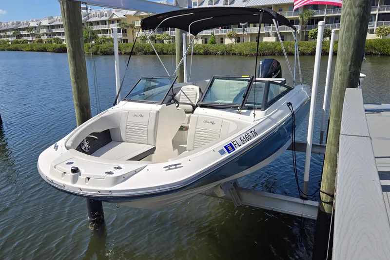 Slide: The Image of 2023 Sea Ray SPX 210 boat docked on a lift by waterfront homes. - 24