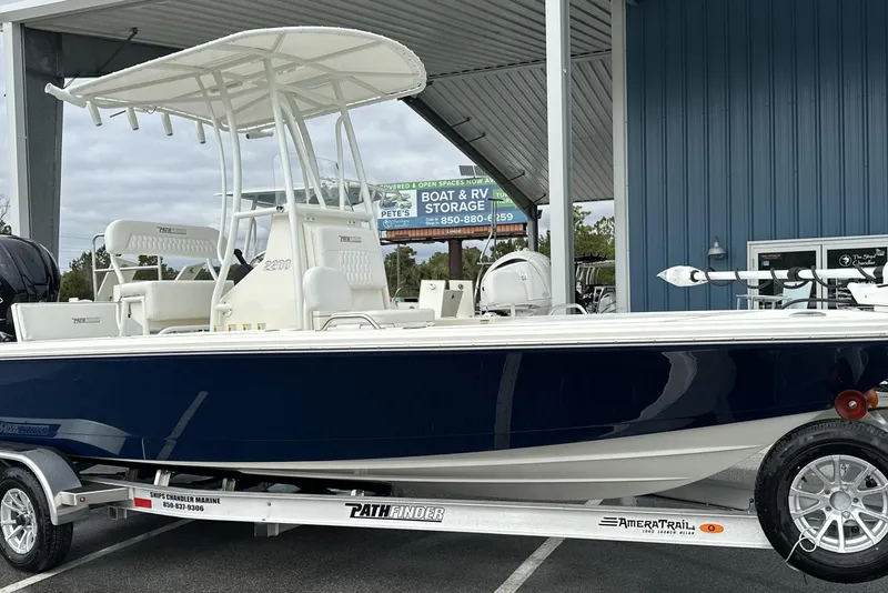 The Image of 2026 Pathfinder 2200 TRS boat on trailer, parked under a metal canopy. - 0