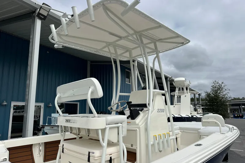 Slide: The Image of 2026 Pathfinder 2200 TRS boat with T-top and seating, docked near blue building. - 18