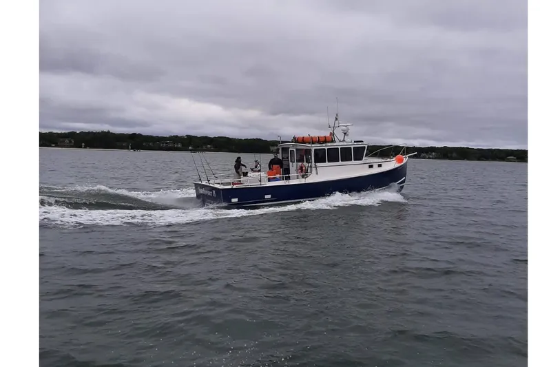 Slide: The Image of 1985 Young Brothers 40 boat cruising on a cloudy day in open water. - 3