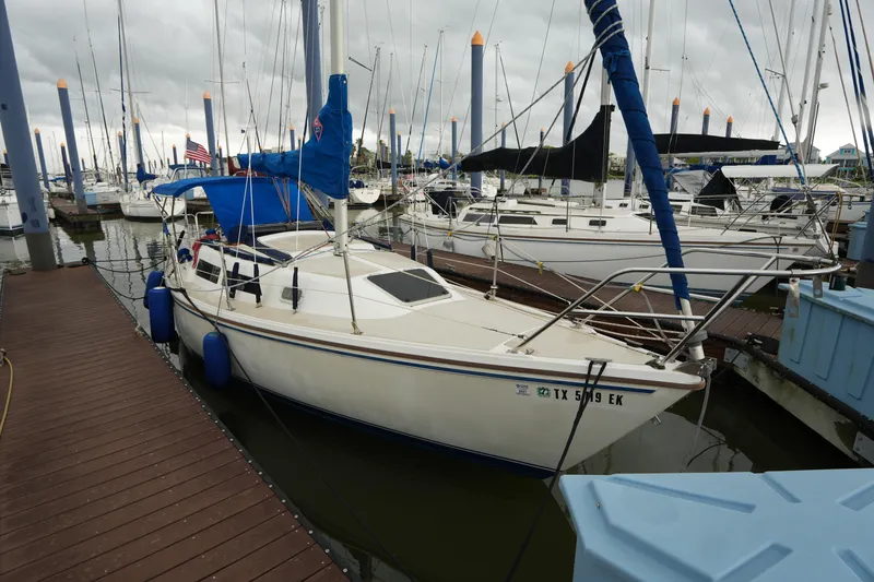 The Image of 1988 Catalina 27 sailboat docked at marina with blue covers and clear sky. - 1