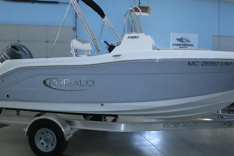 Slide: The Image of 2021 Robalo R180 Center Console boat on trailer in showroom. - 2
