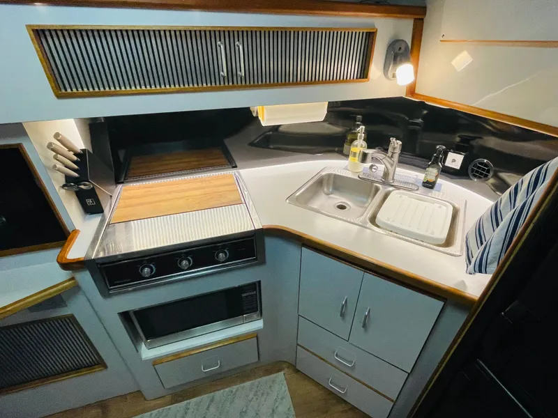 Slide: The Image of 1989 Sea Ray 390 Express Cruiser kitchen with sink and stove. - 49