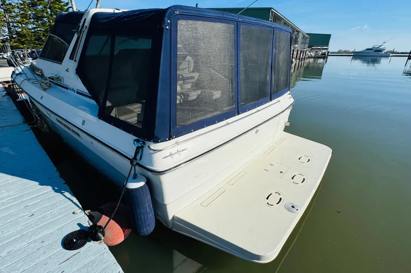 Slide: The Image of 1989 Sea Ray 390 Express Cruiser docked, featuring a covered rear deck and calm waters. - 8