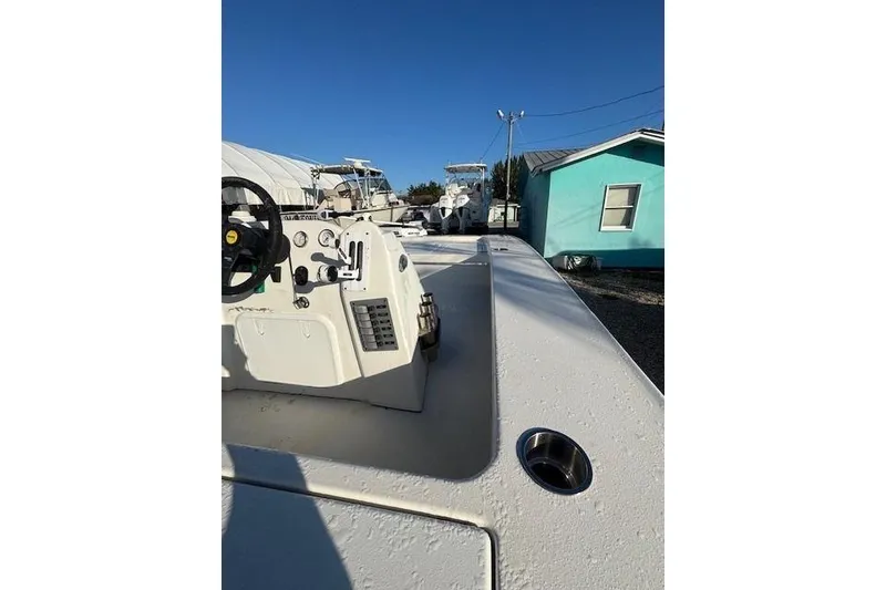 Slide: The Image of 2007 Talon F21 boat deck with steering console, parked near a turquoise house. - 11
