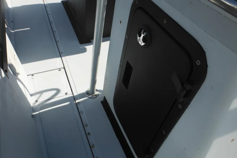Slide: The Image of 1990 Boston Whaler Guardian 22 interior with black storage compartment and metal railing. - 15