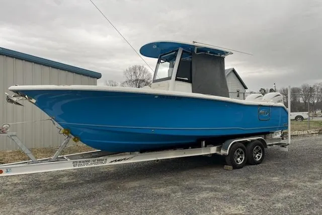 The Image of 2025 Sea Hunt Ultra 265 SE boat on trailer, vibrant blue hull, parked outdoors. - 0