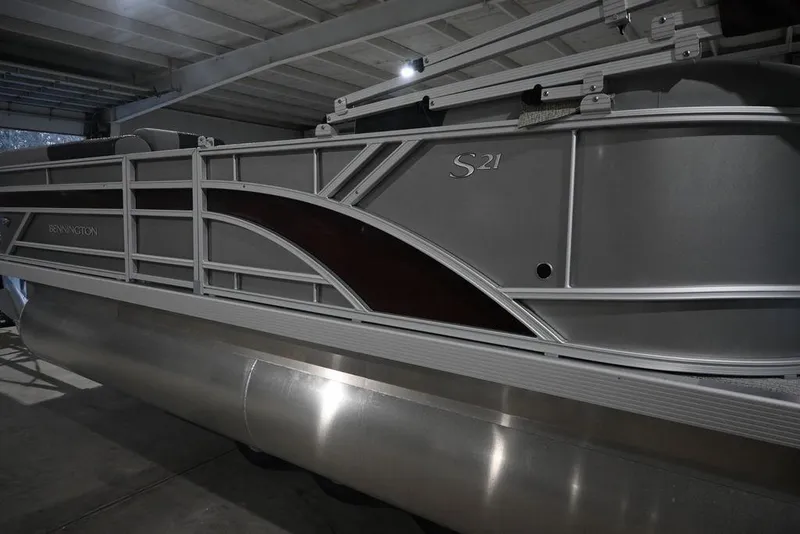 Slide: The Image of 2026 Bennington S Quad Bench 21 SSR pontoon boat in a dimly lit indoor setting. - 3