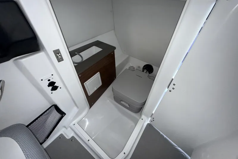 Slide: The Image of Interior of 2026 Scarab 255 SE boat featuring compact bathroom amenities. - 19