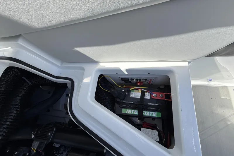Slide: The Image of Battery compartment of 2026 Scarab 255 SE boat, featuring Interstate battery and wiring. - 29