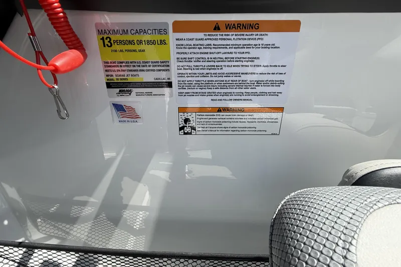 Slide: The Image of Warning labels and capacity information on a 2026 Scarab 255 SE boat. - 30