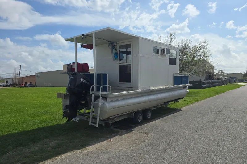 Slide: The Image of 2003 Godfrey 24 pontoon boat with Suzuki motor on trailer, parked on roadside. - 2