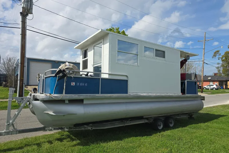 Slide: The Image of 2003 Godfrey 24 pontoon boat on trailer, parked on grass under blue sky. - 8