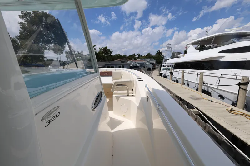 Slide: The Image of 2019 Cobia 320 Center Console boat docked, showcasing sleek design and spacious deck. - 15