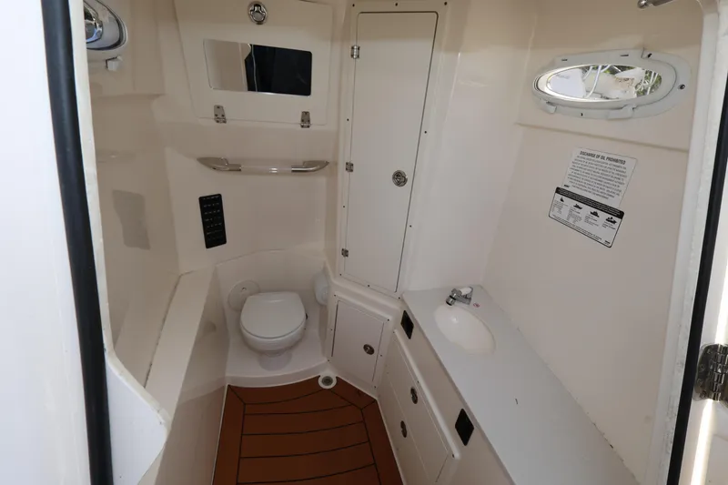 Slide: The Image of 2019 Cobia 320 Center Console boat bathroom interior with toilet and sink. - 19