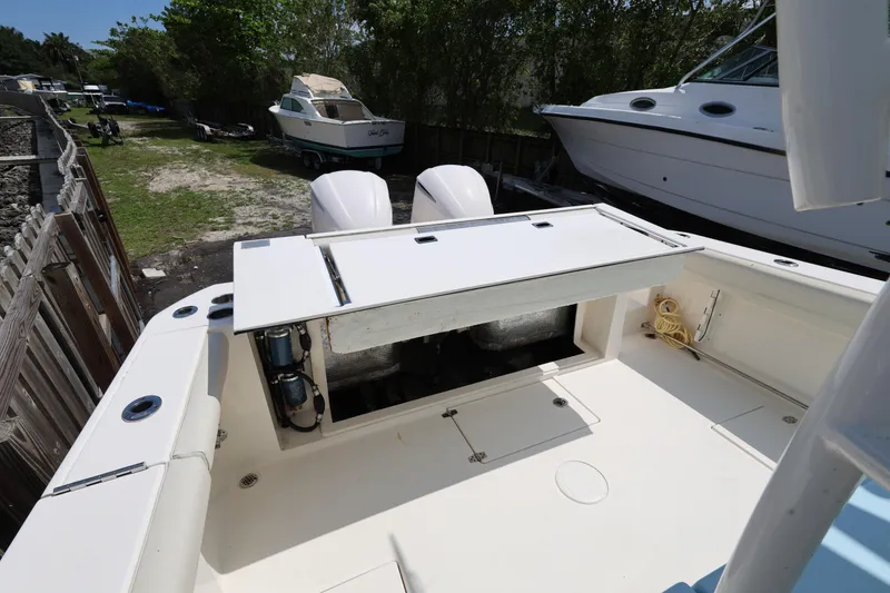 Slide: The Image of 2019 Cobia 320 Center Console boat with open storage compartment, docked outdoors. - 23