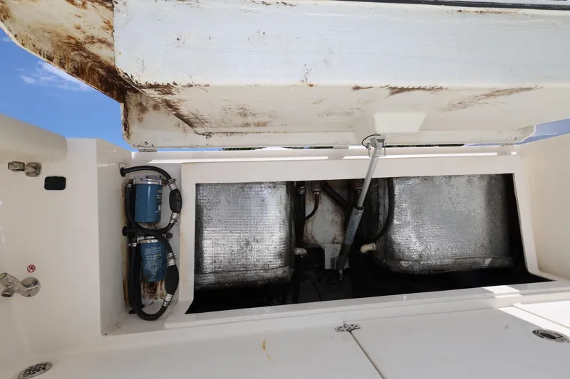Slide: The Image of 2019 Cobia 320 Center Console boat storage compartment with visible wiring and components. - 25